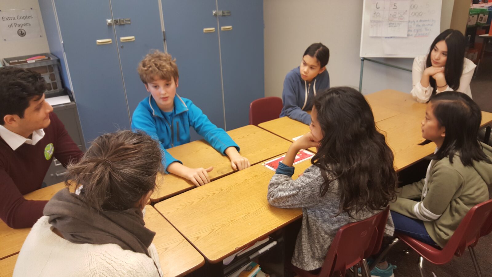 students and teachers at talking on desk group